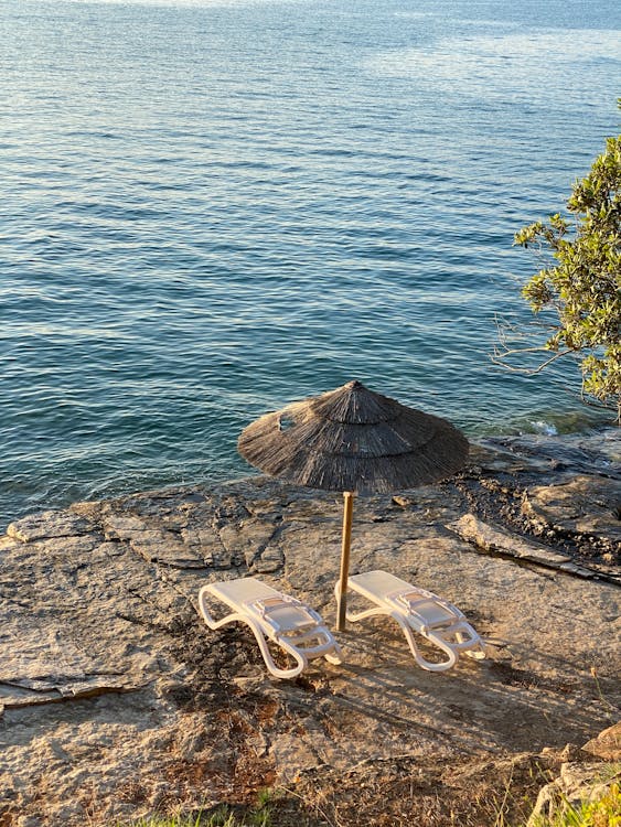Transats et parasol en paille sur les rochers face à la mer — farniente à Cassis