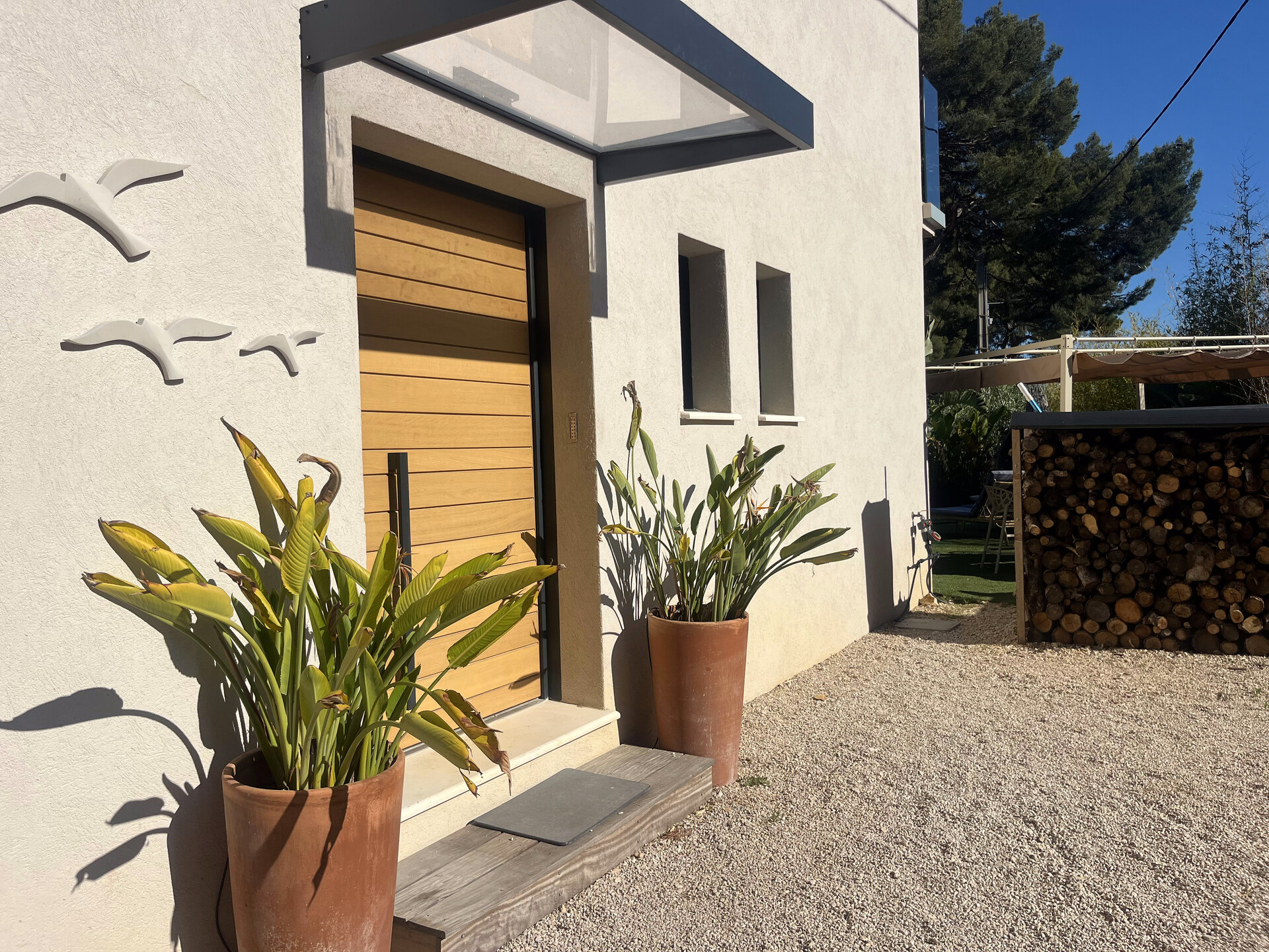 Entrée villa avec porte bois clair et plantes tropicales — accueil chaleureux Villa CosyBlu Cassis